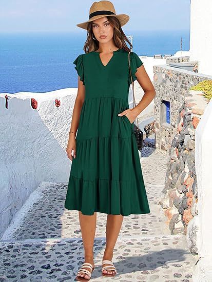 Woman in a green dress and hat standing on a picturesque Mediterranean street.